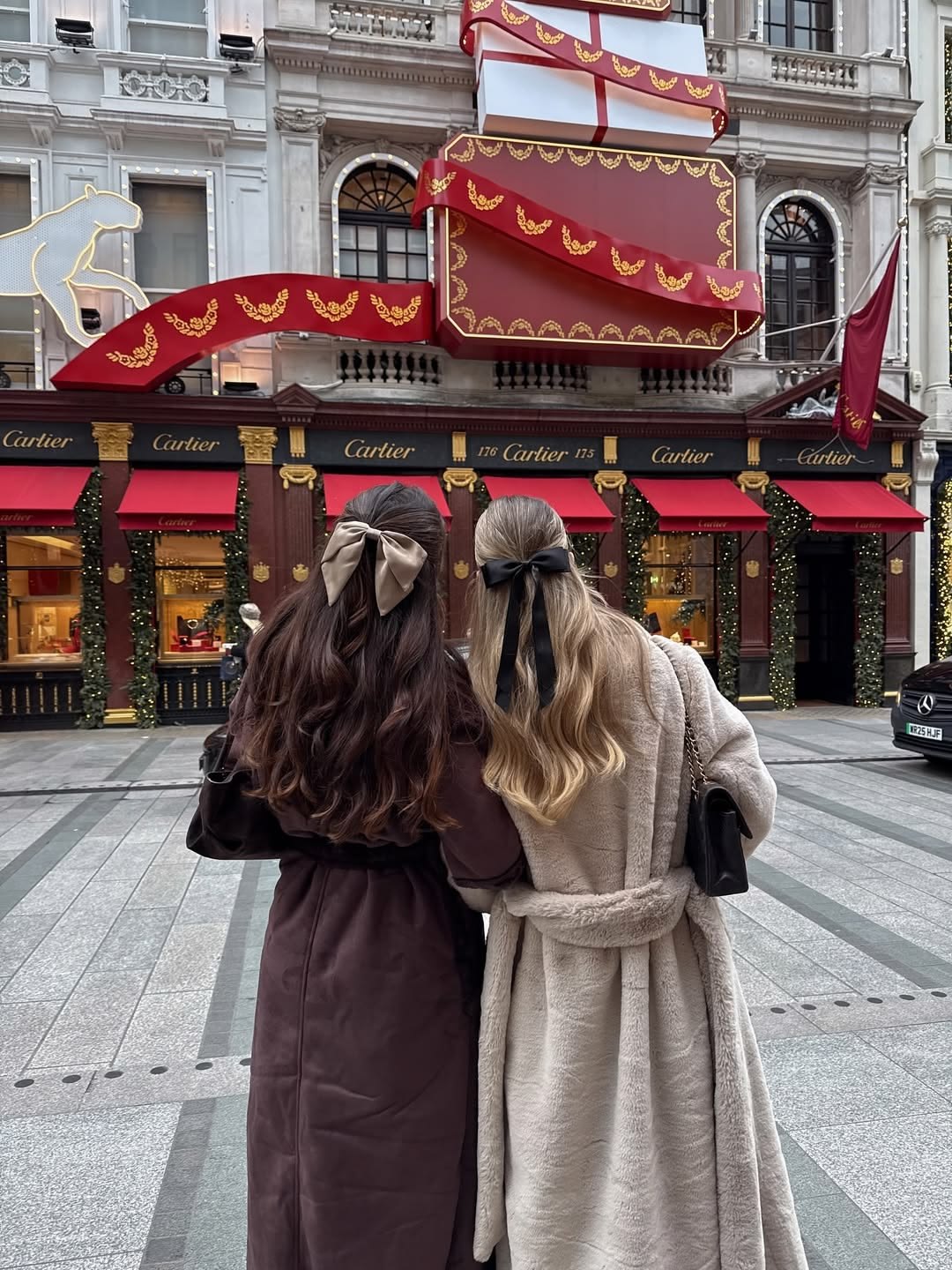 Twee meiden met strikken in hun haar voor de versierde Cartier-winkel in Londen